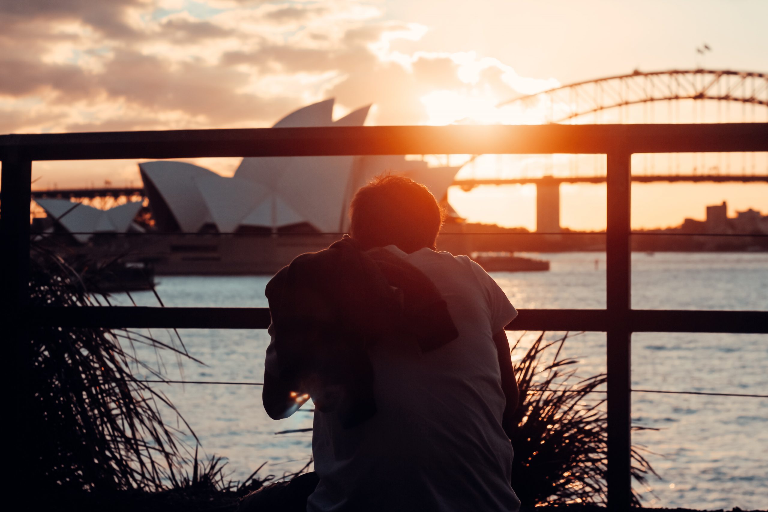 man in front of opera house taking a photo at sunset at Mrs Macquarie's Chair (The Domain)