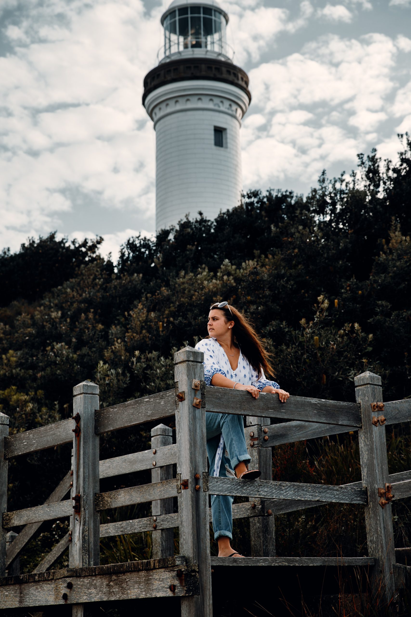 woman standing in front of Norah head lighthouse looking out at the beach and ocean