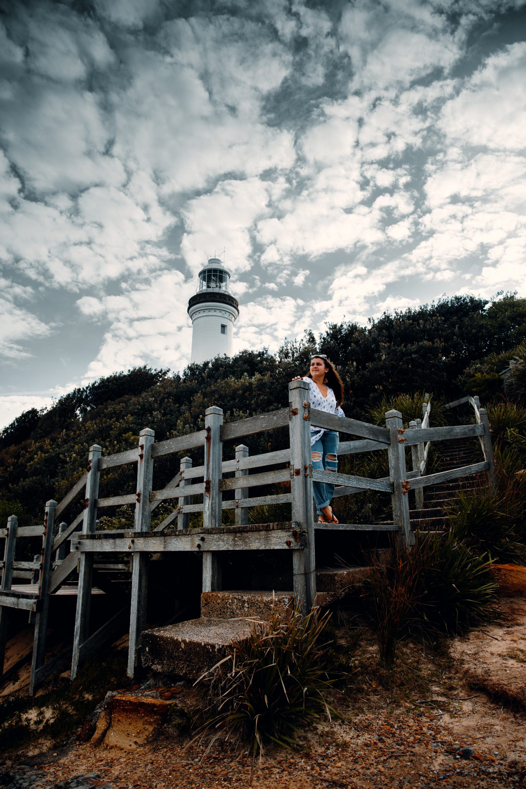 woman standing in front of Norah head lighthouse looking out at the beach and ocean