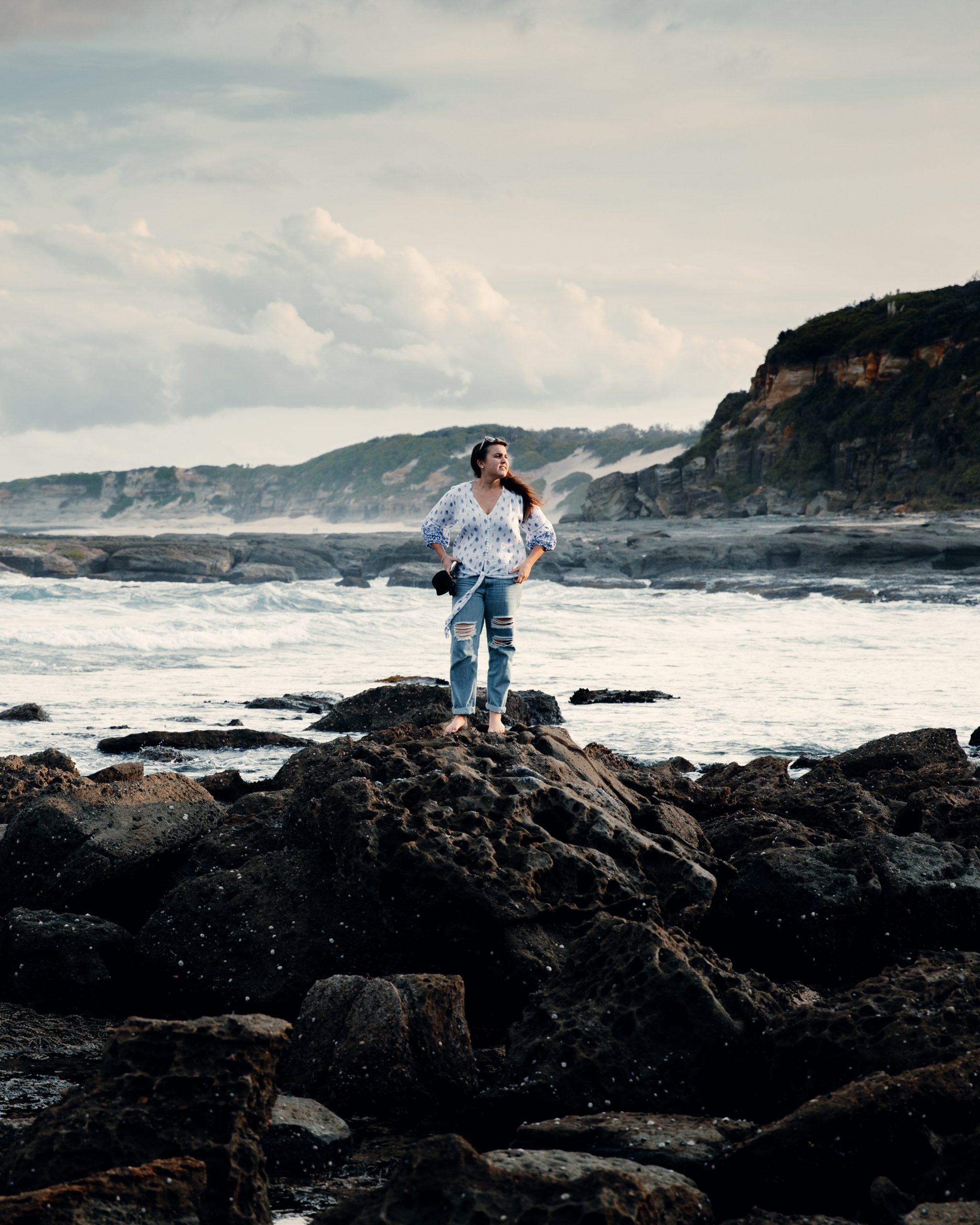 woman standing on rock pools in front ocean landscape at Norah head