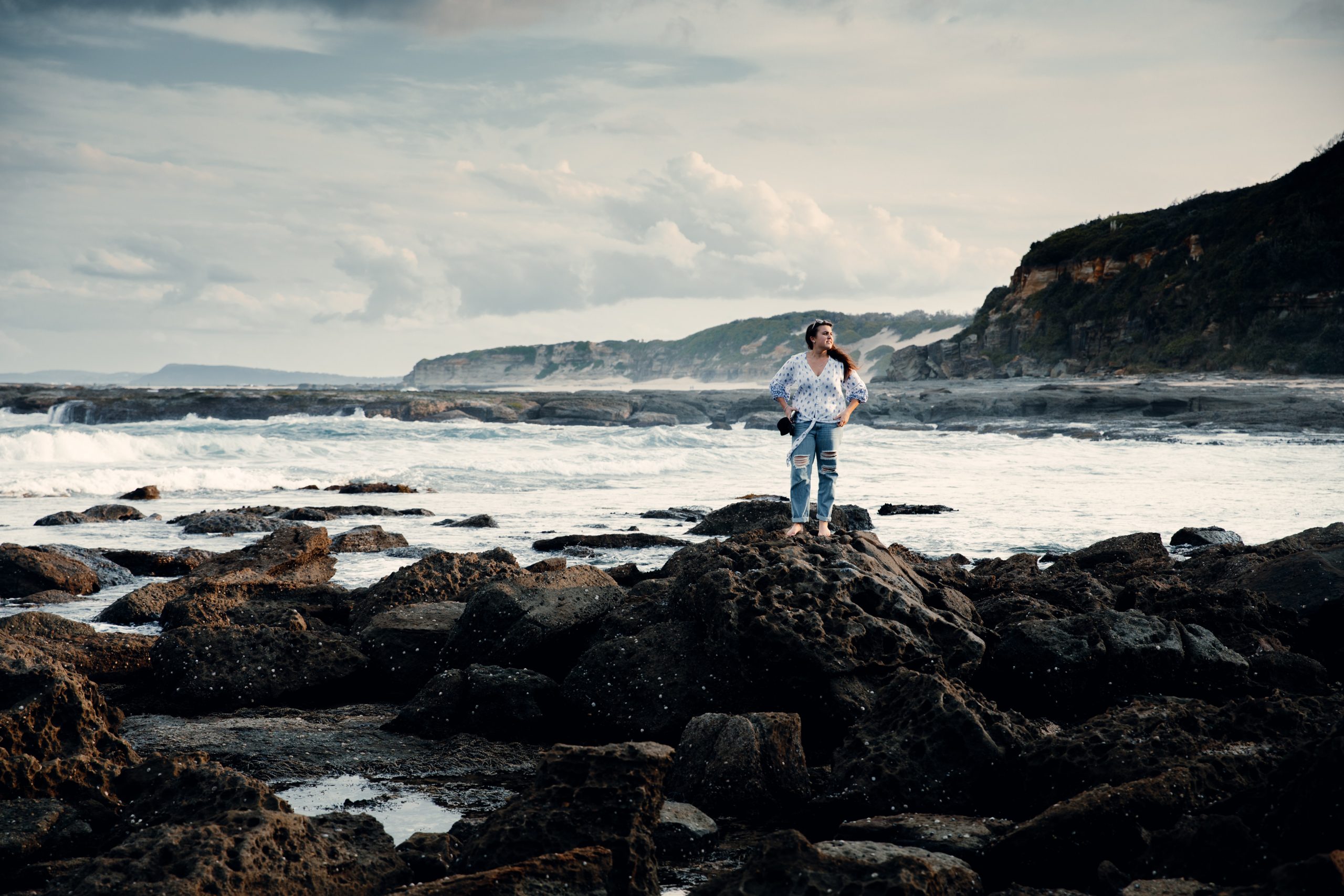 woman standing on rock pools in front ocean landscape at Norah head