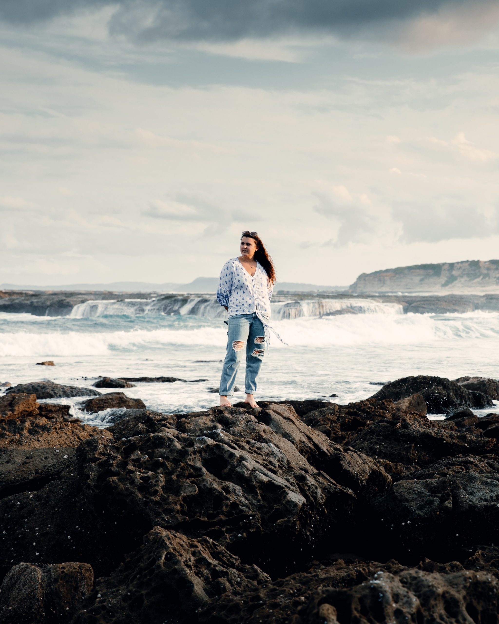 woman standing on rock pools in front ocean landscape at Norah head