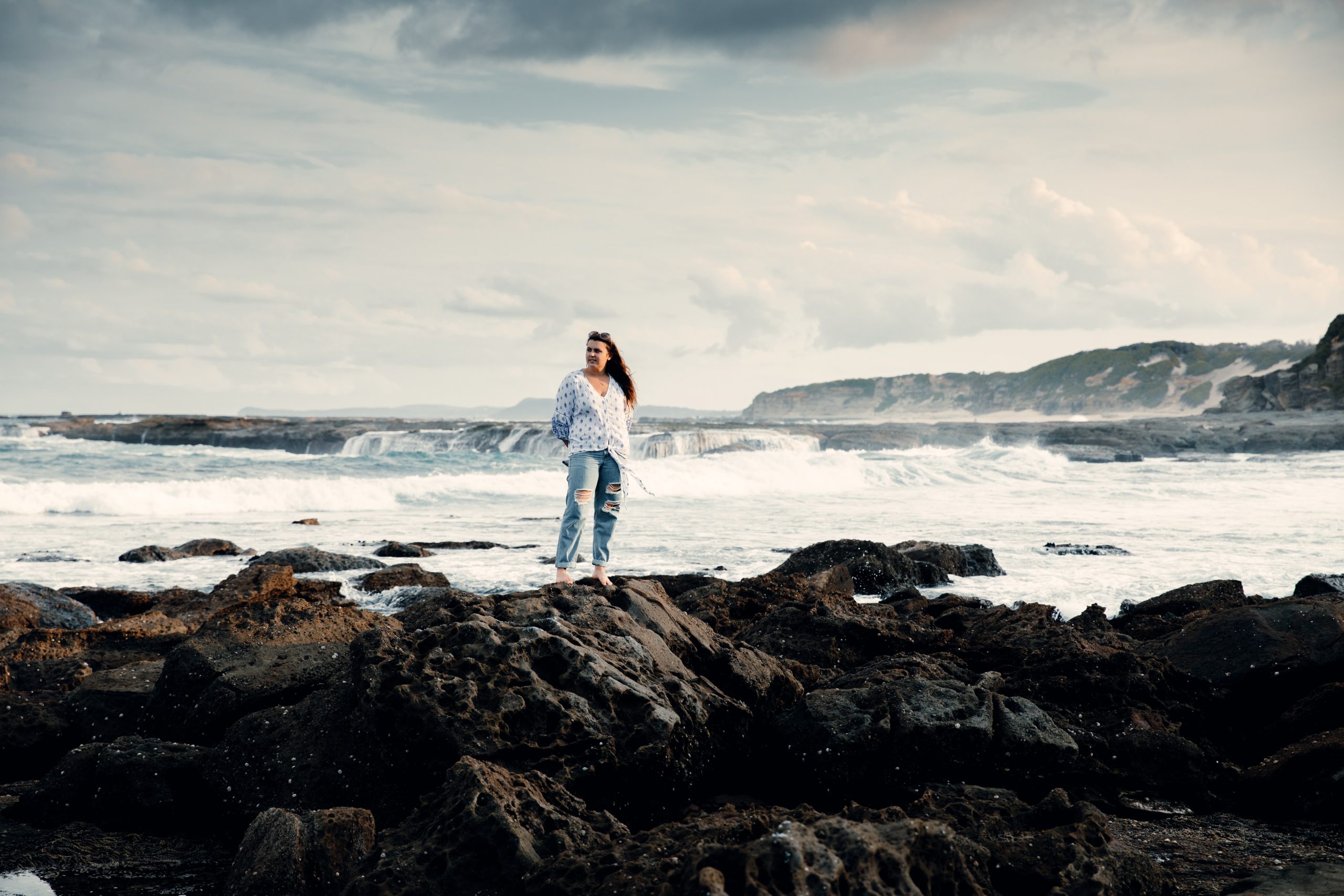 woman standing on rock pools in front ocean landscape at Norah head