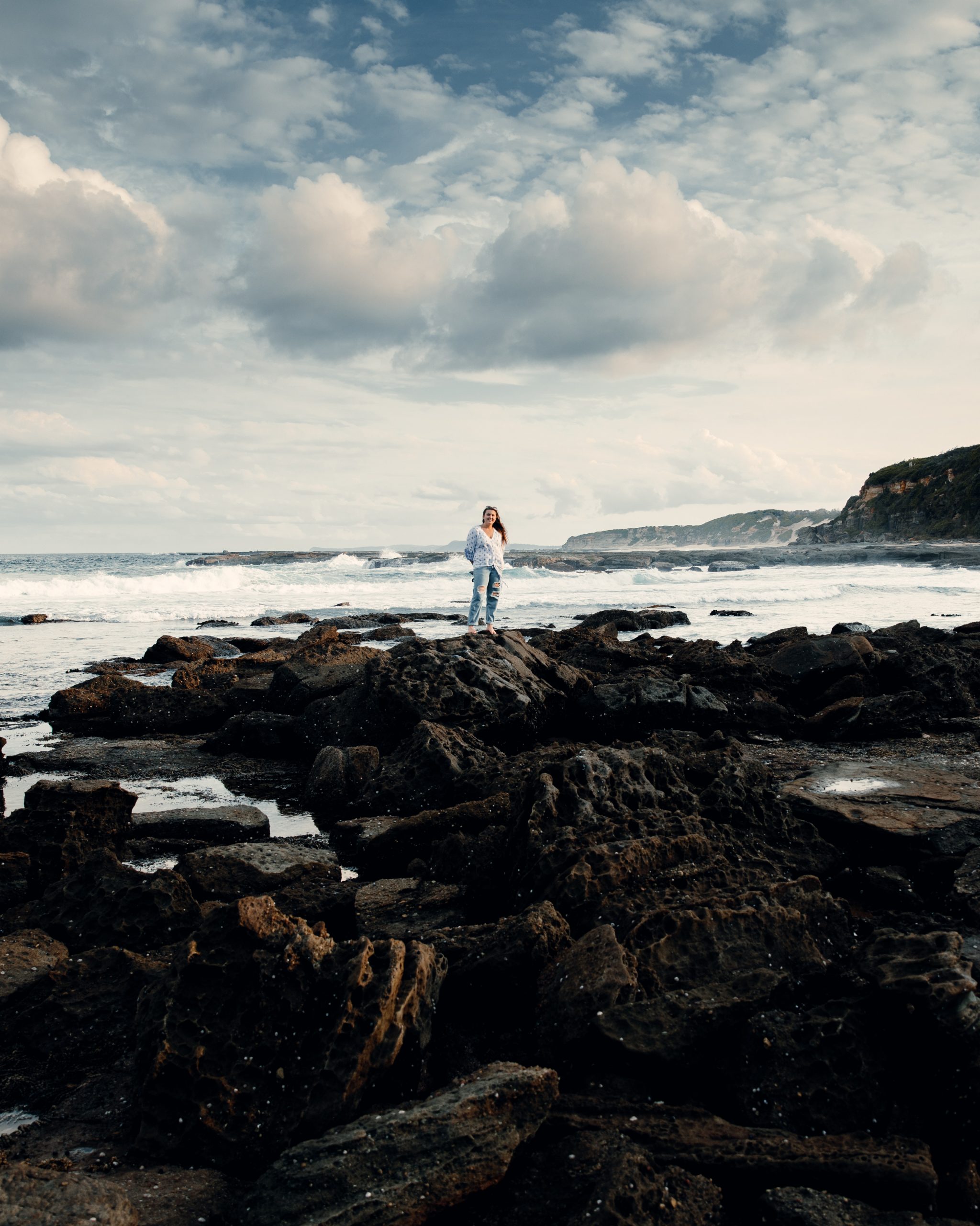 woman standing on rock pools in front ocean landscape at Norah head