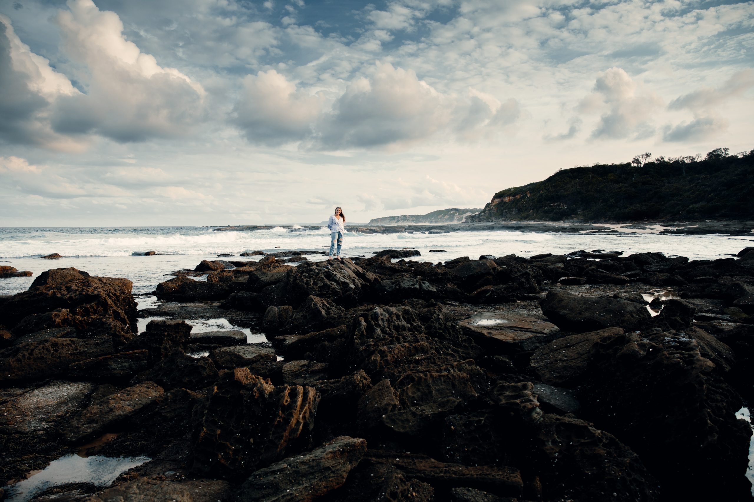 woman standing on rock pools in front ocean landscape at Norah head