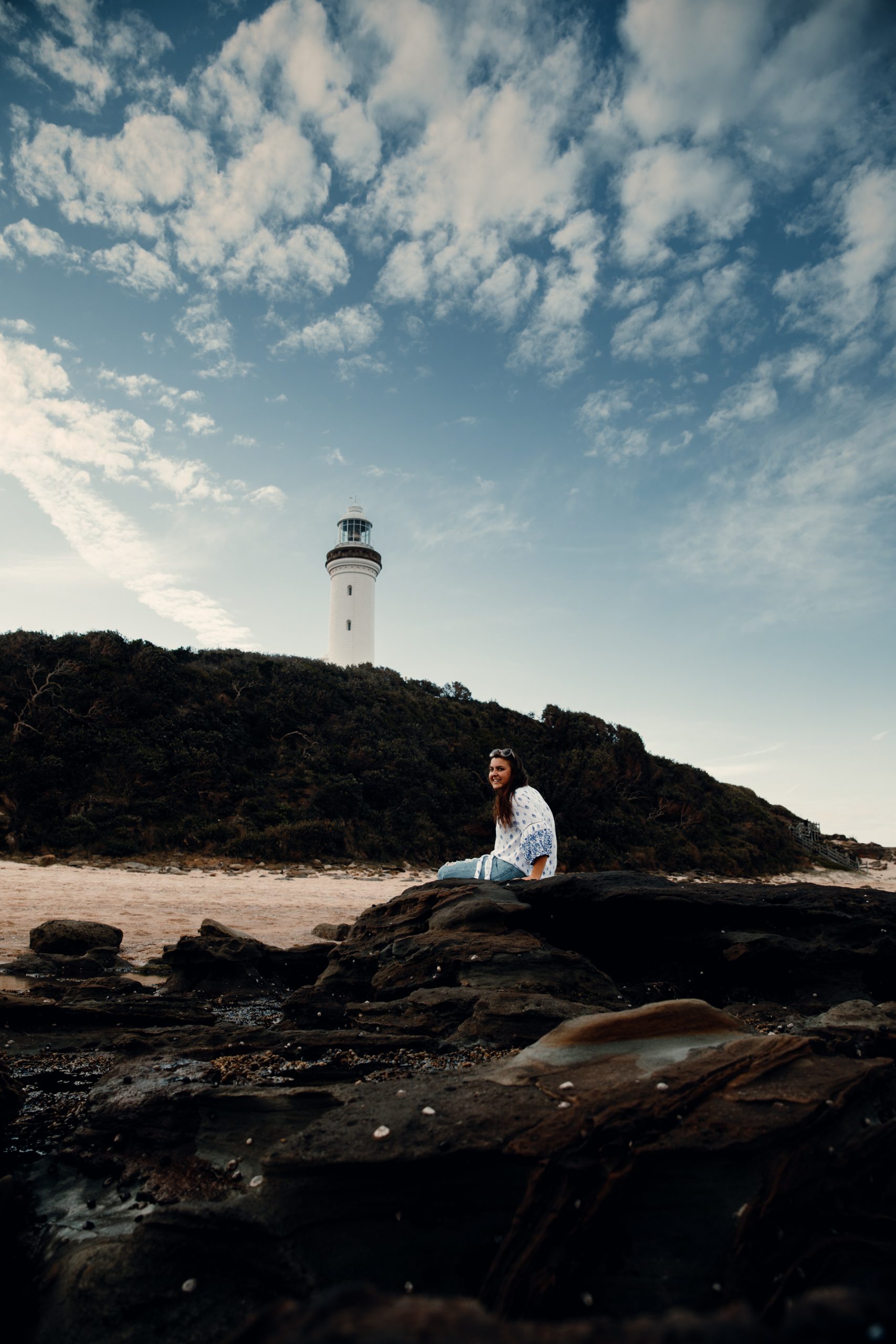 woman sitting in front of Norah head lighthouse at rock pools