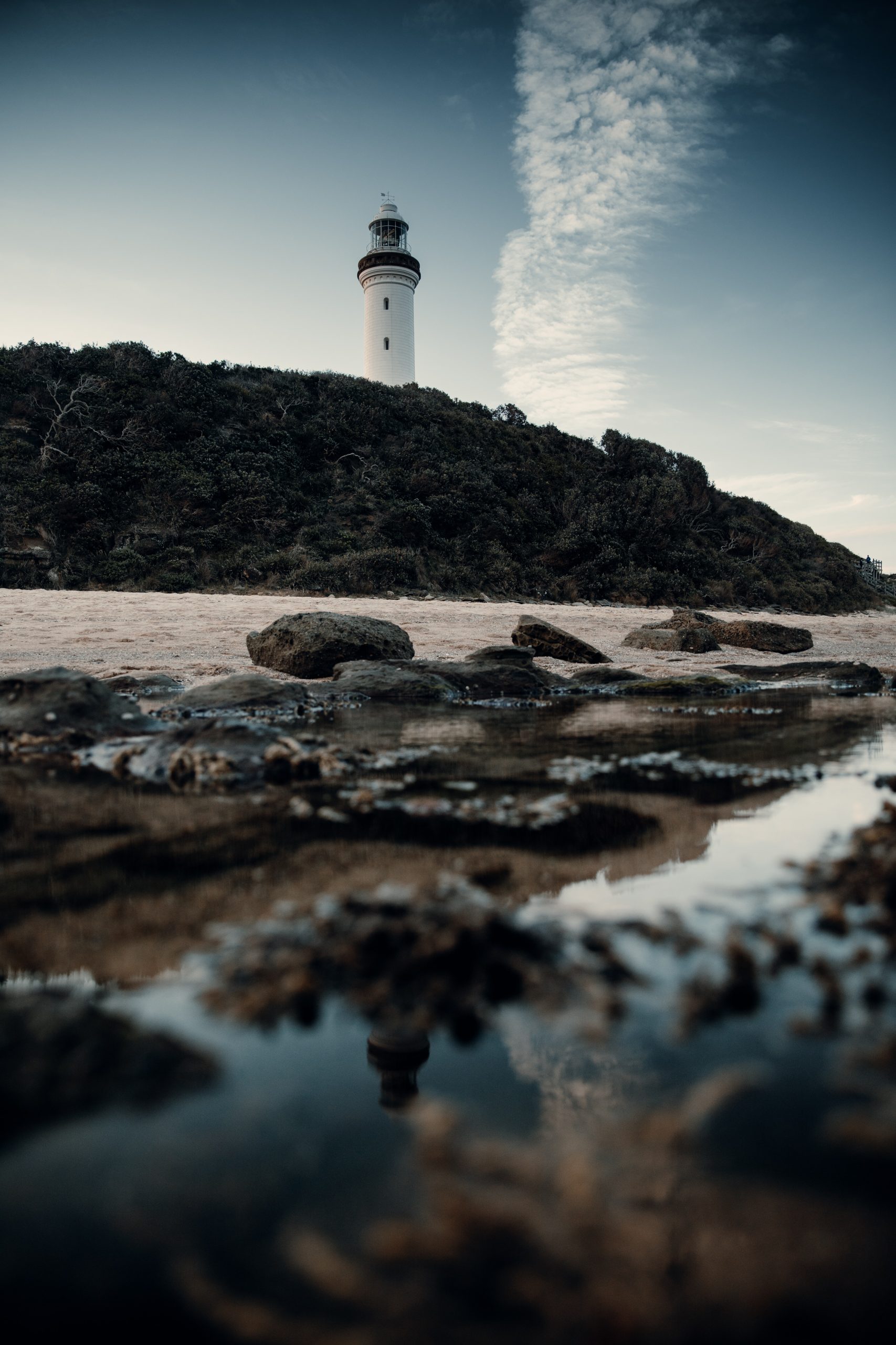 Norah head lighthouse viewed from the beach reflecting in rock pools