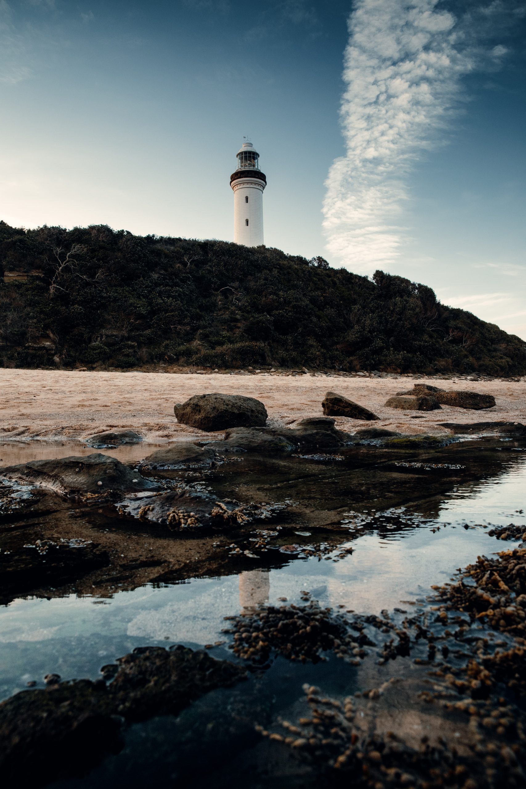 Norah head lighthouse viewed from the beach reflecting in rock pools
