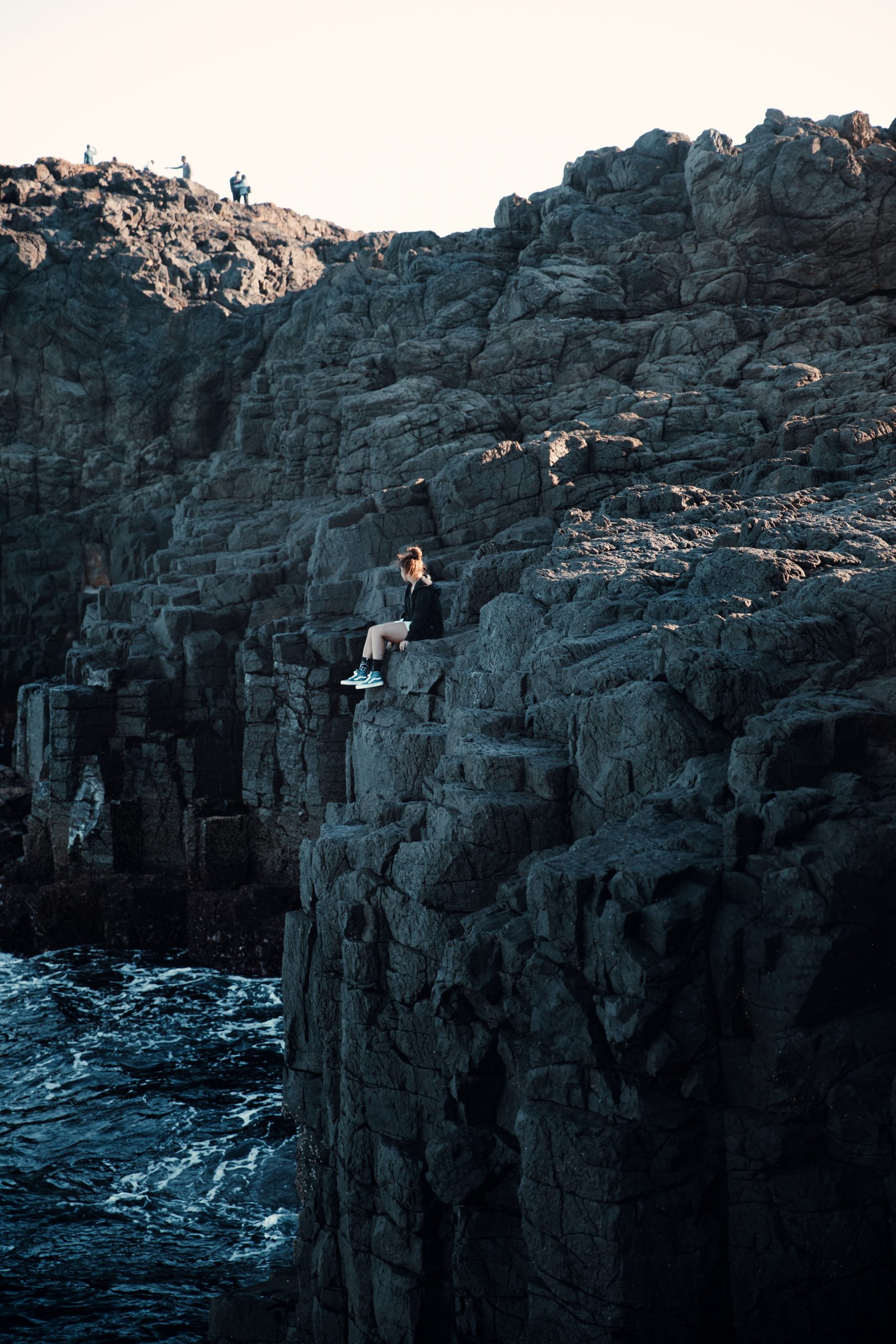 woman sitting on cliff over the ocean at Kiama blowhole
