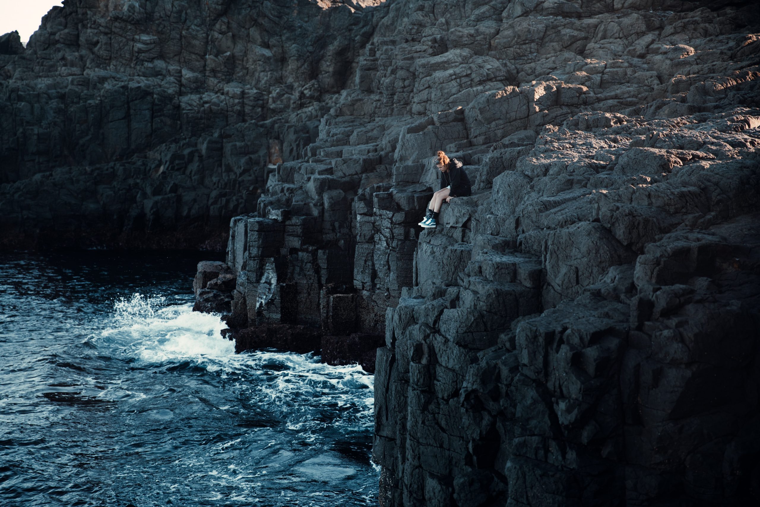 travel photography - woman sitting on cliff over the ocean at Kiama blowhole 