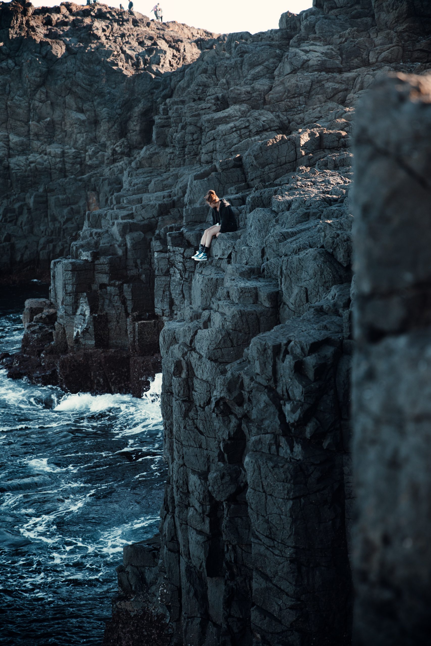 woman sitting on cliff over the ocean at Kiama blowhole