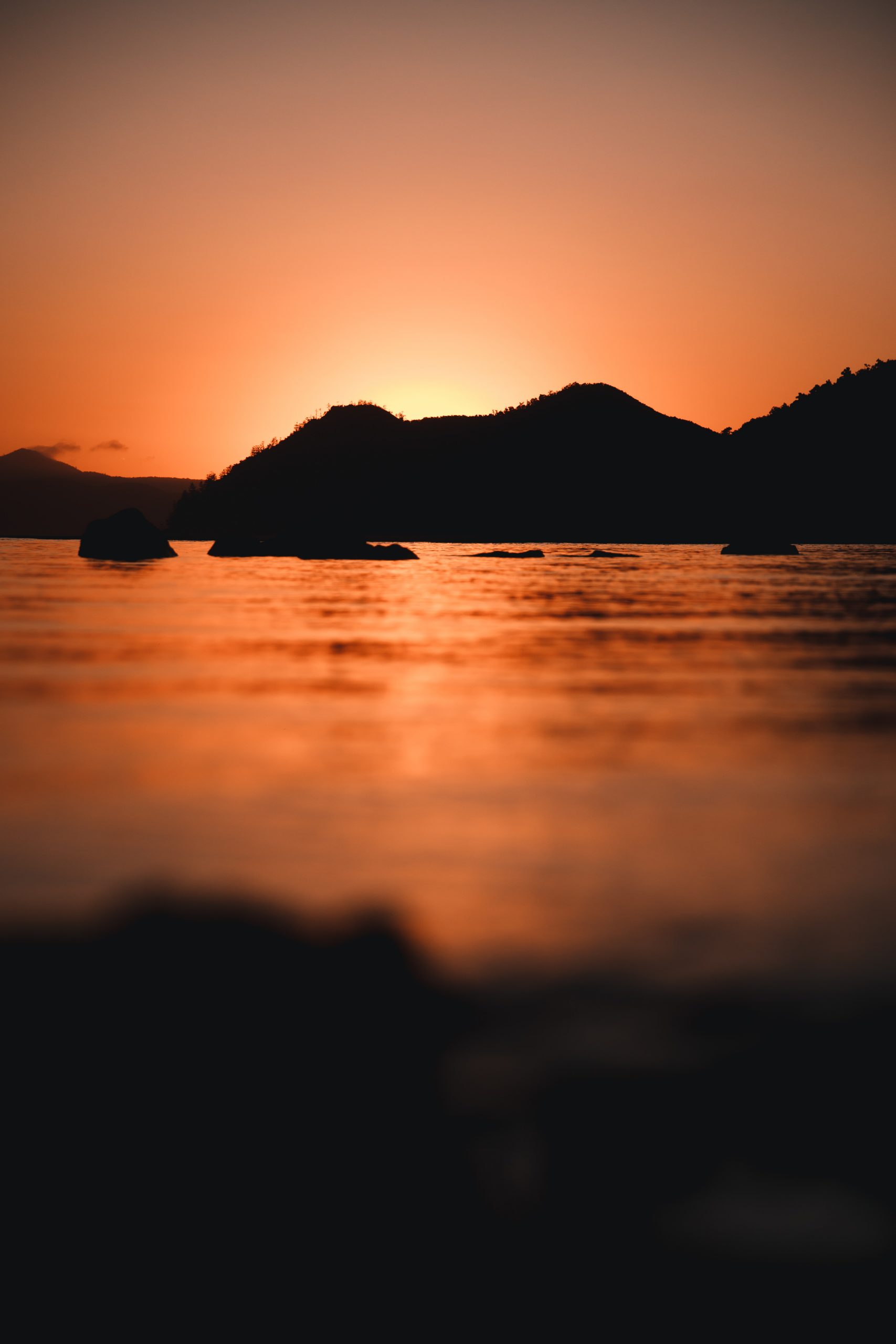 sun peaking through island mountain in the whitsunday islands during incredible sunrise (Whitsunday Islands, Queensland Australia)