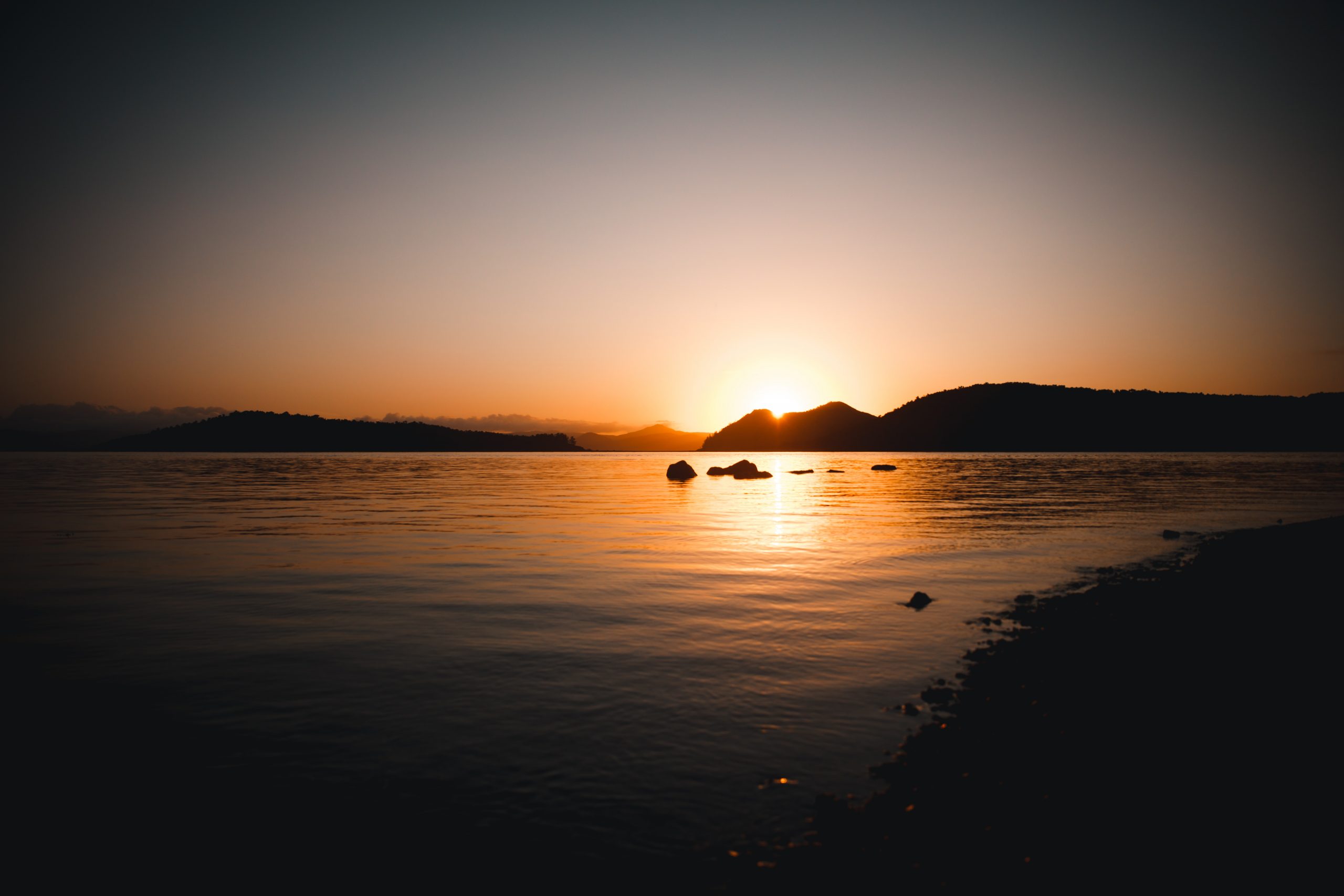 sun peaking through island mountain in the whitsunday islands during incredible sunrise