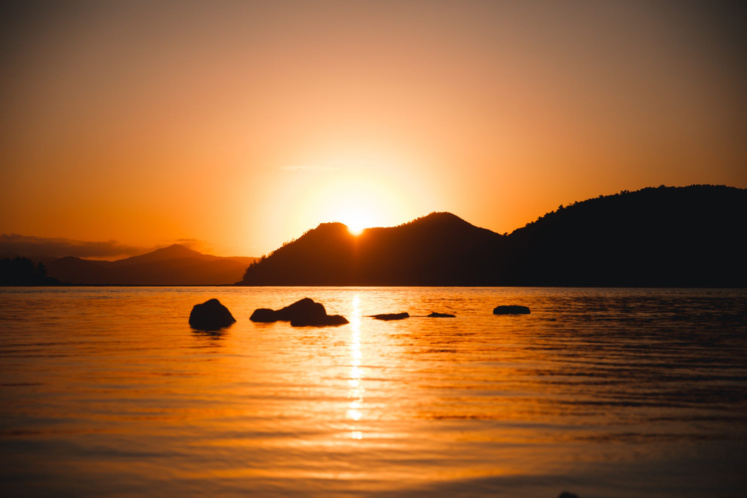 sun peaking through island mountain in the whitsunday islands during incredible sunrise