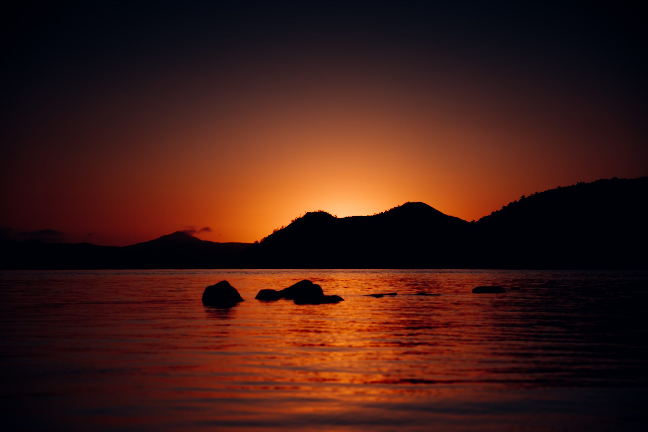 sun peaking through island mountain in the whitsunday islands during incredible sunrise