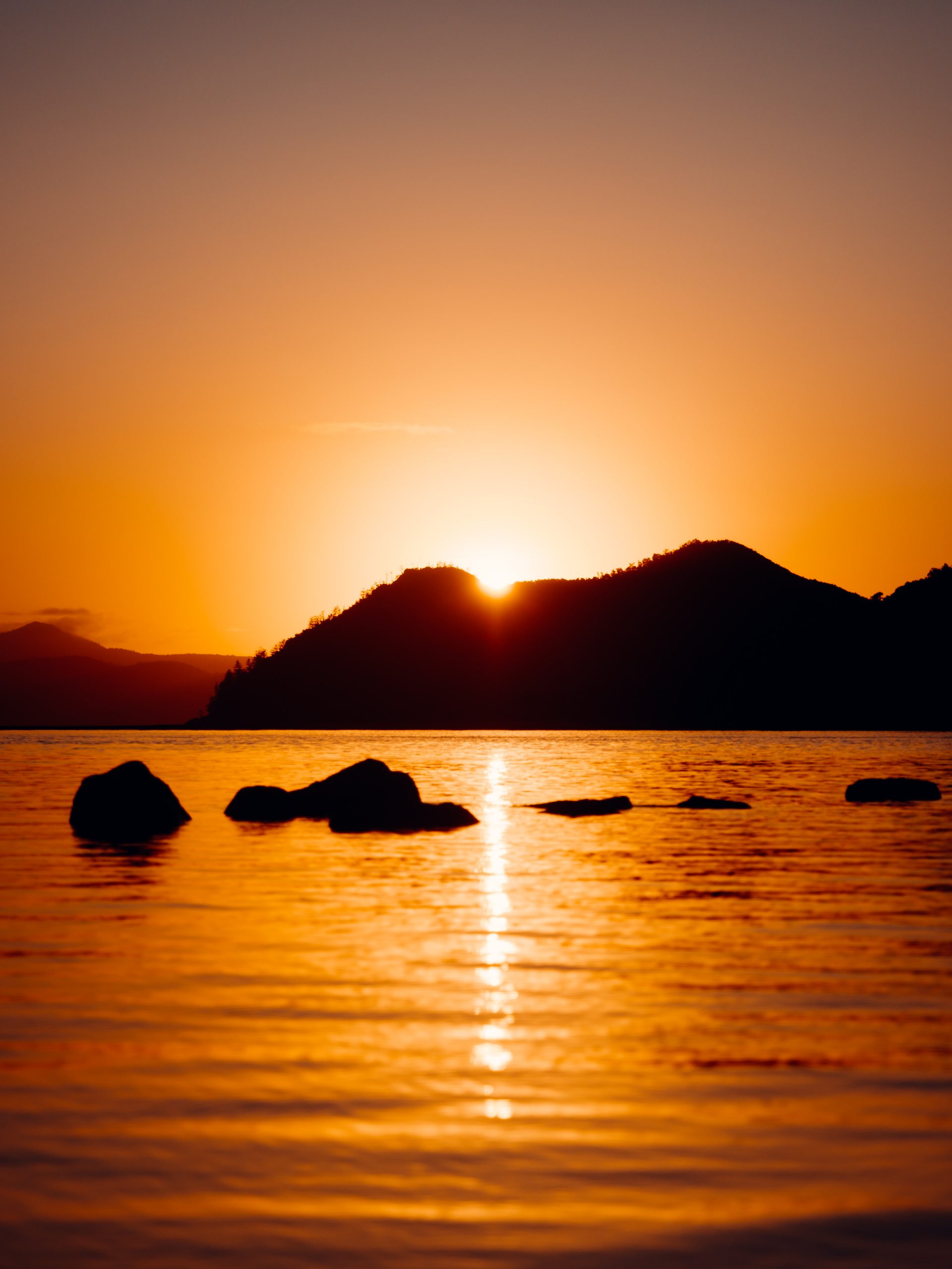 sun peaking through island mountain in the whitsunday islands during incredible sunrise