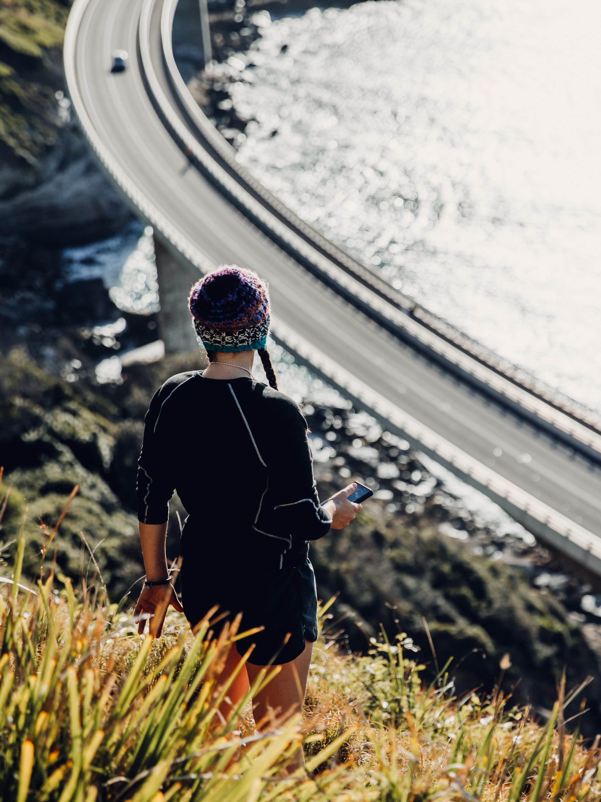 woman looking down at Seacliff bridge at sunrise from a secret hiking trail