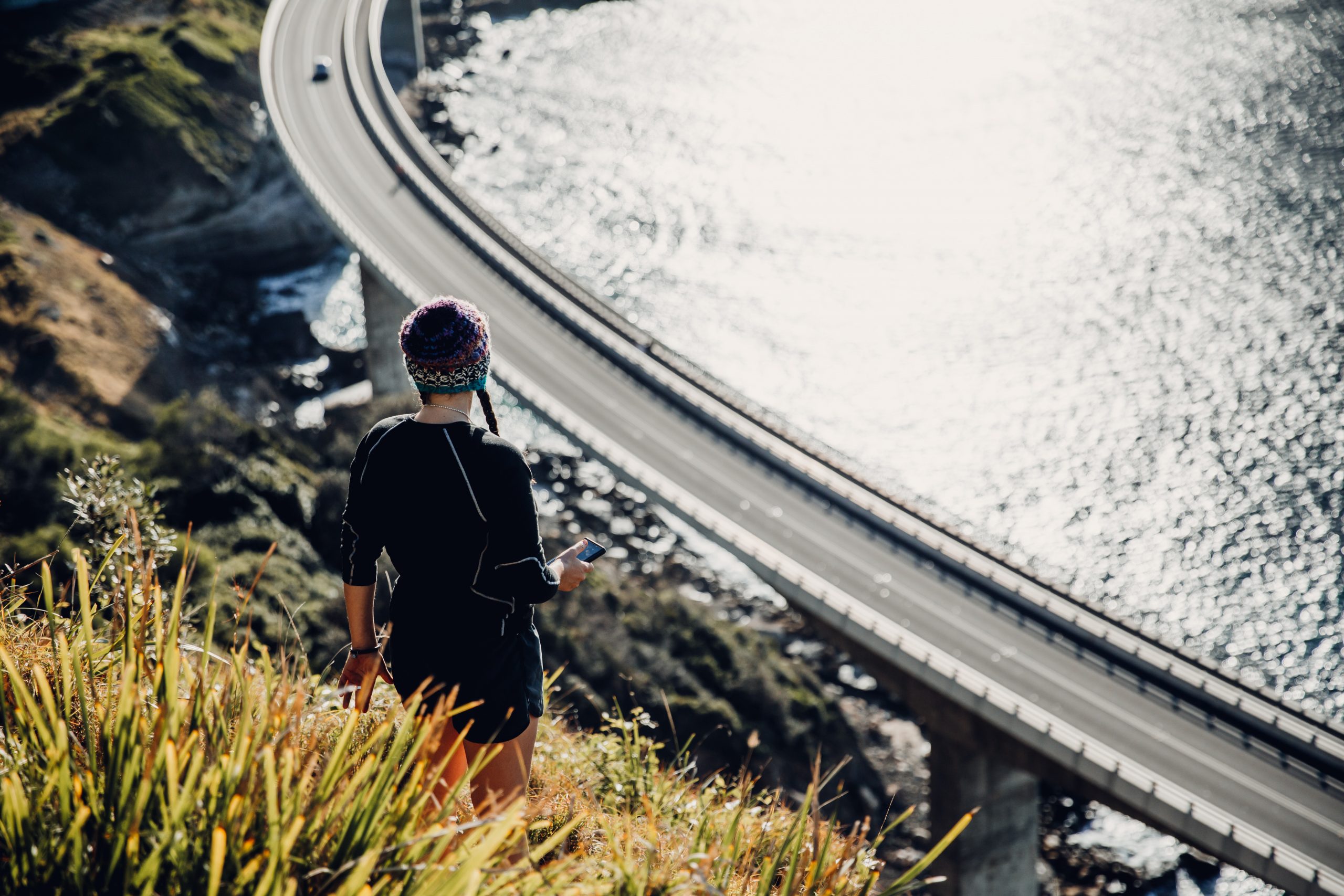 woman looking down at Seacliff bridge at sunrise from a secret hiking trail